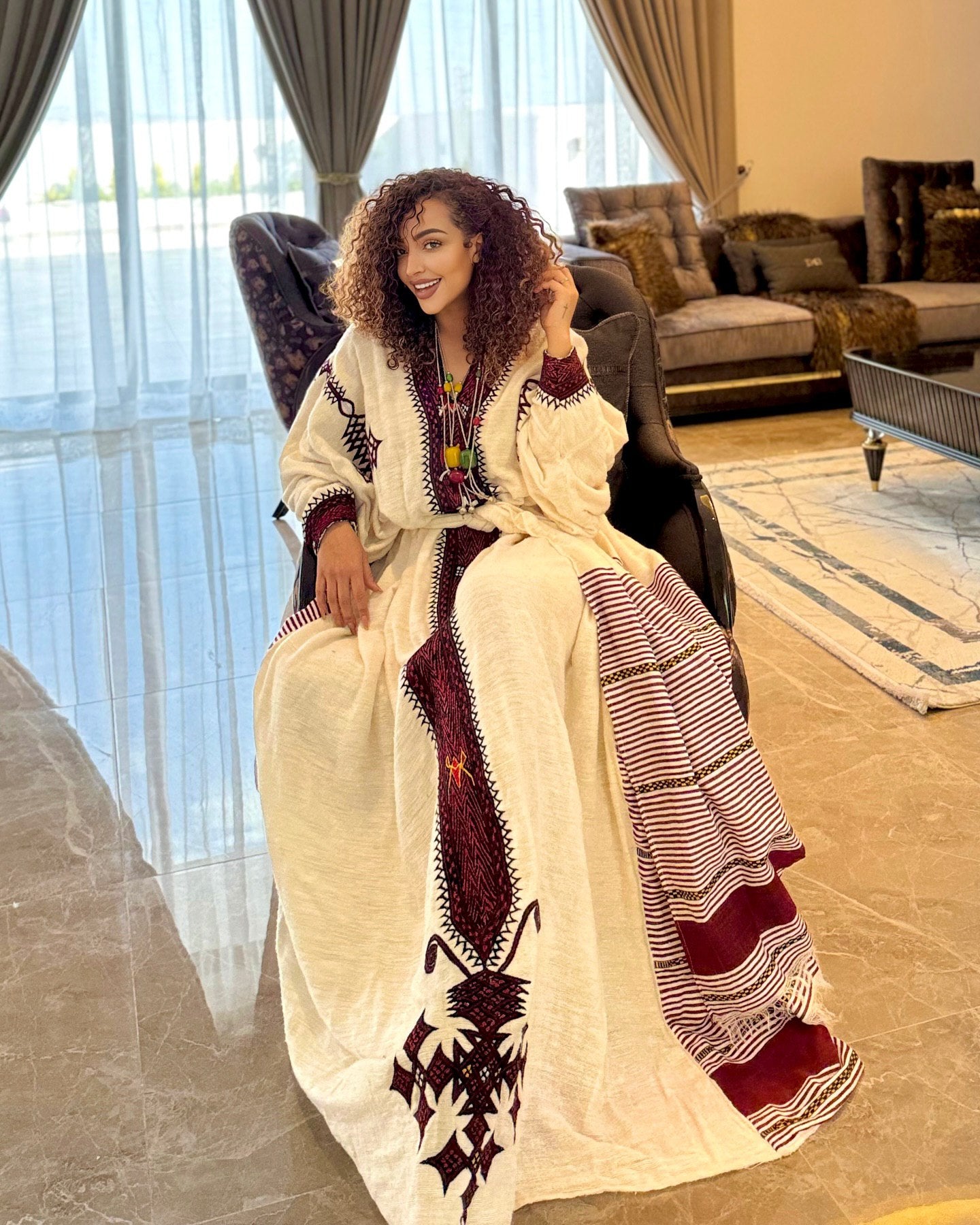 Woman in a traditional outfit sitting in a modern living room.