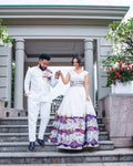 Couple in formal attire standing on steps outside a building with decorative elements.