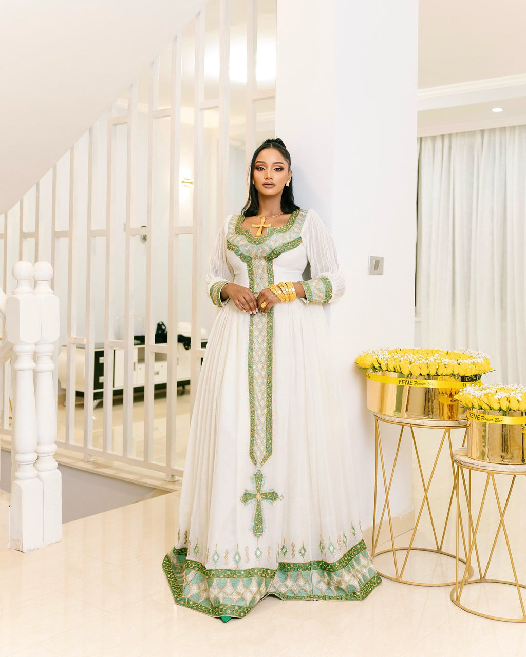 Woman in a white and green dress standing in a bright, elegant interior setting.
