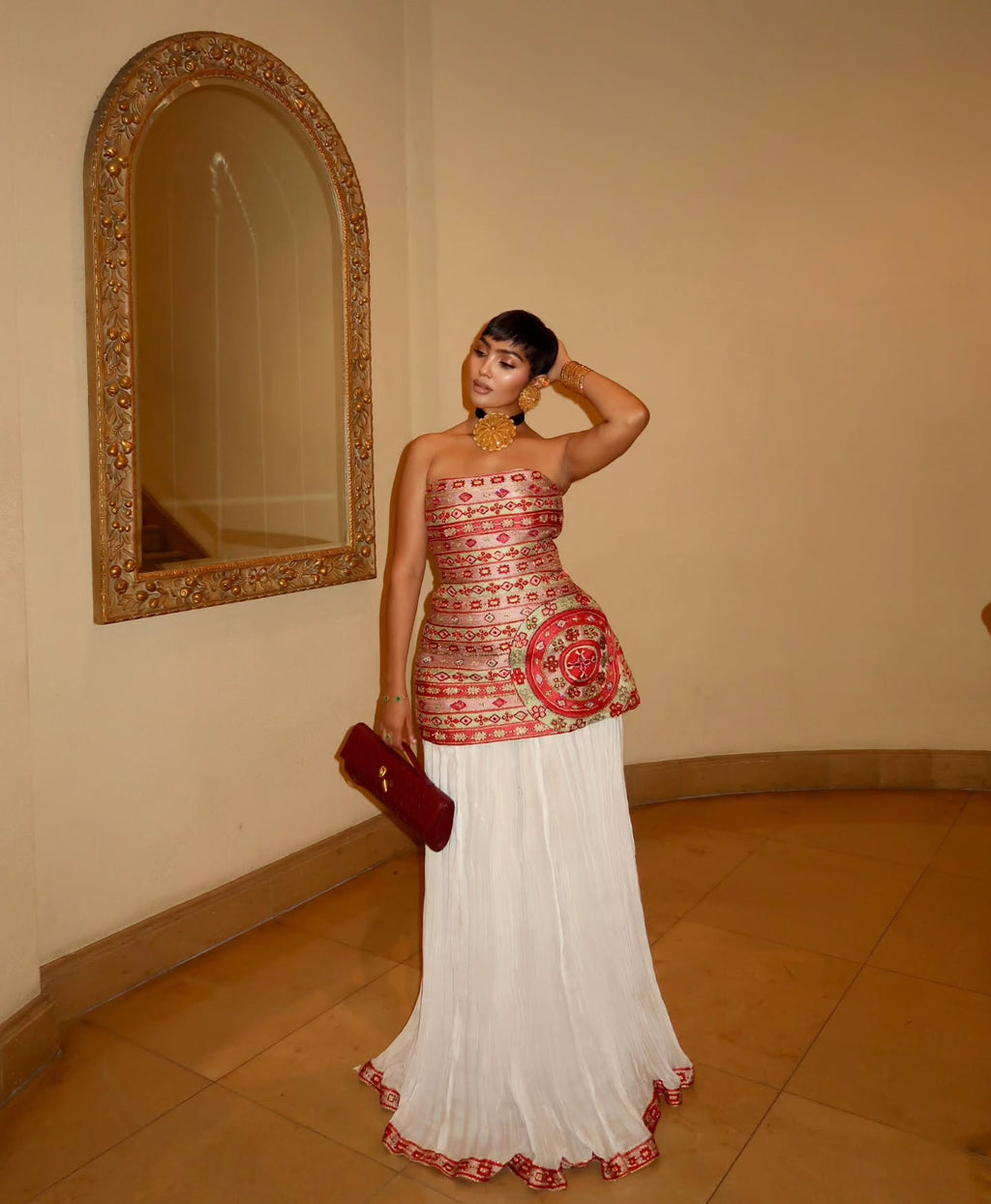 Woman in a red and white traditional outfit standing in front of a mirror.