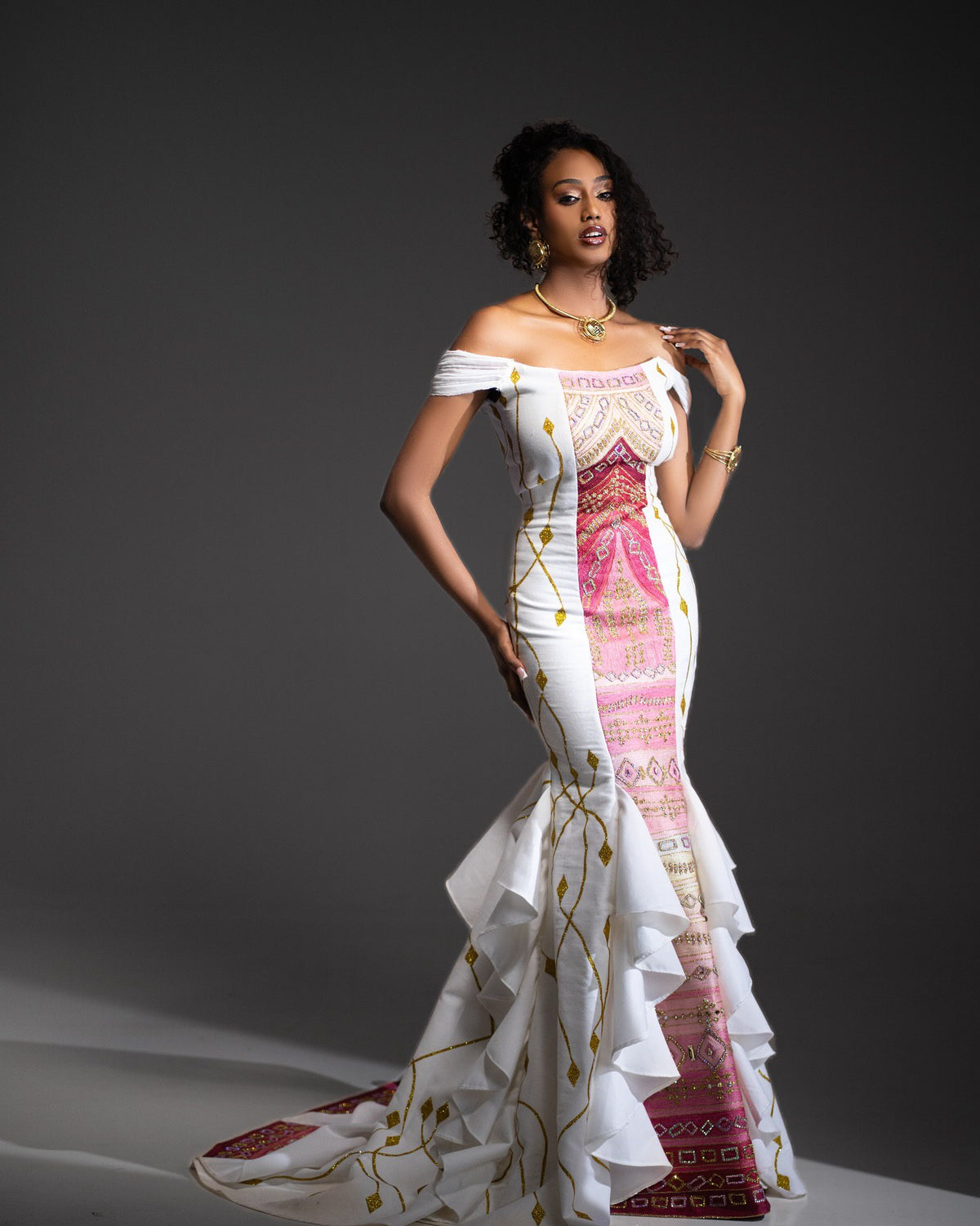 Model wearing a white dress with colorful patterns on a dark background
