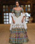 Woman wearing a traditional outfit with intricate patterns in a blurred indoor setting