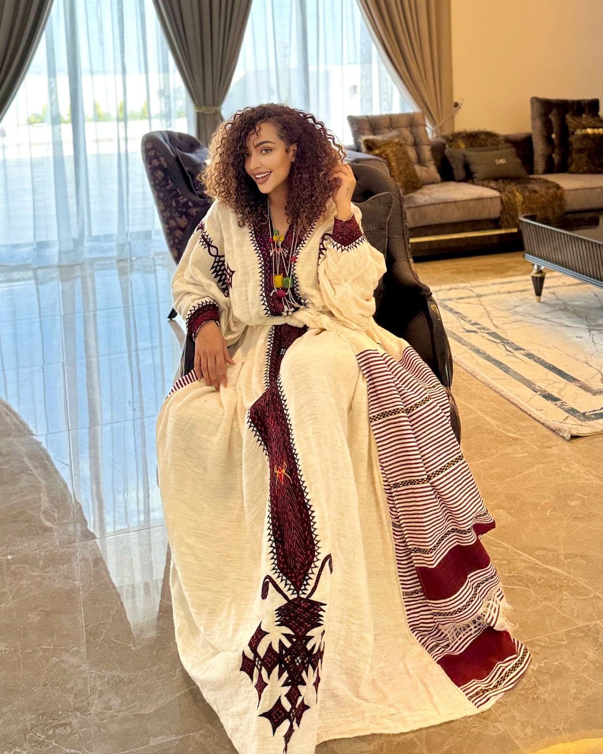 Woman in a traditional outfit sitting in a modern living room.