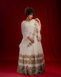 Woman in a white and patterned traditional outfit against a red background