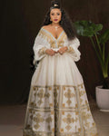 Woman wearing a white dress with gold embroidery in a dark setting