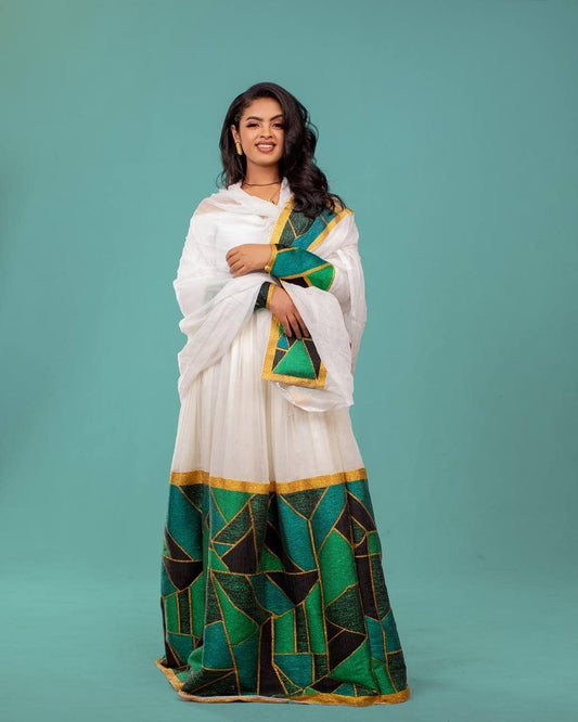 Woman wearing a white saree with green and gold patterns on a teal background