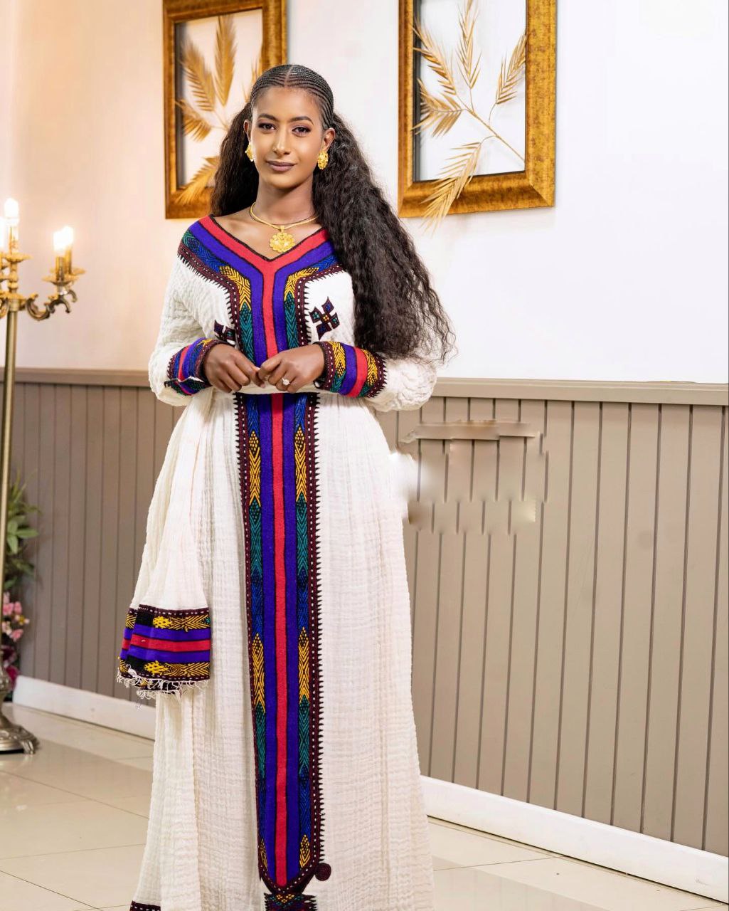 Woman wearing a traditional outfit with colorful patterns in an indoor setting.