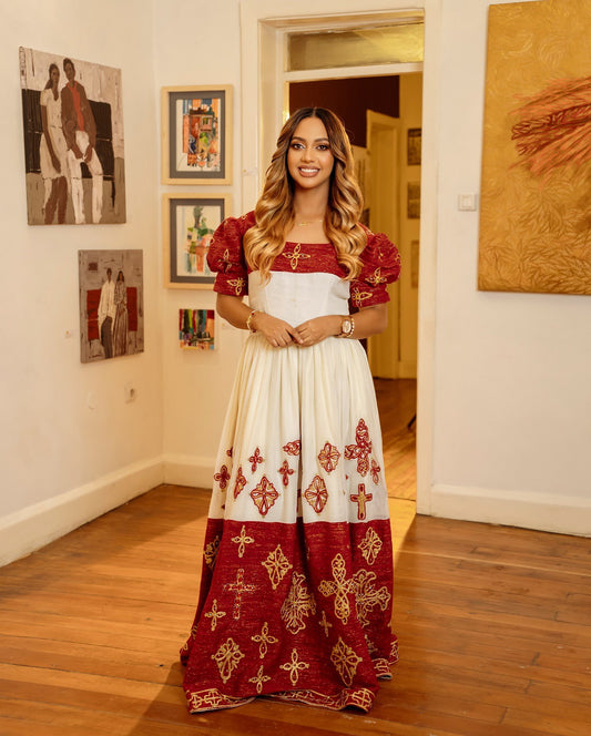 Woman in a red and white dress with intricate patterns standing in an art gallery.